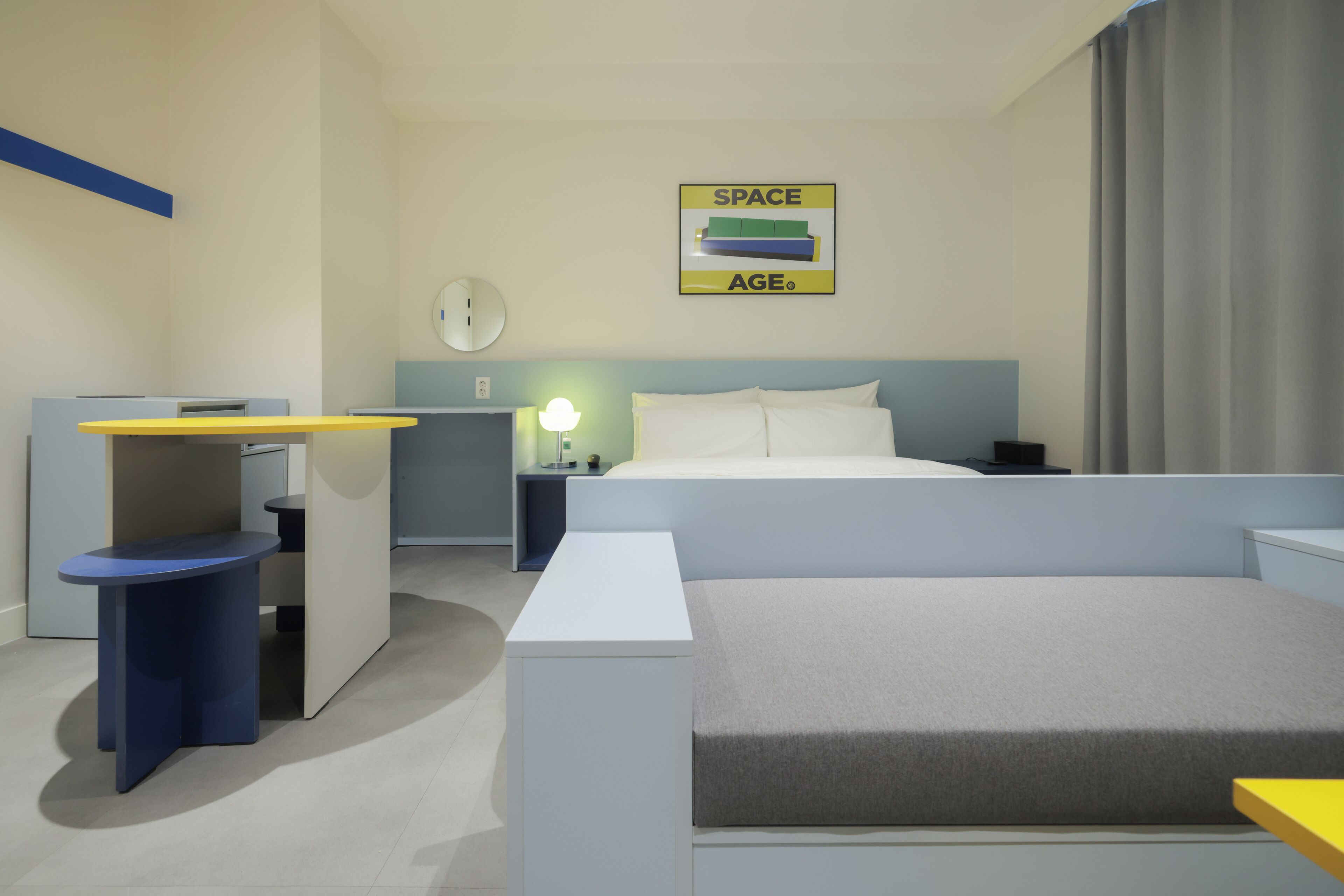 Una habitación de hotel moderna con cama, escritorio, silla, mesita de noche y un reloj de pared.
