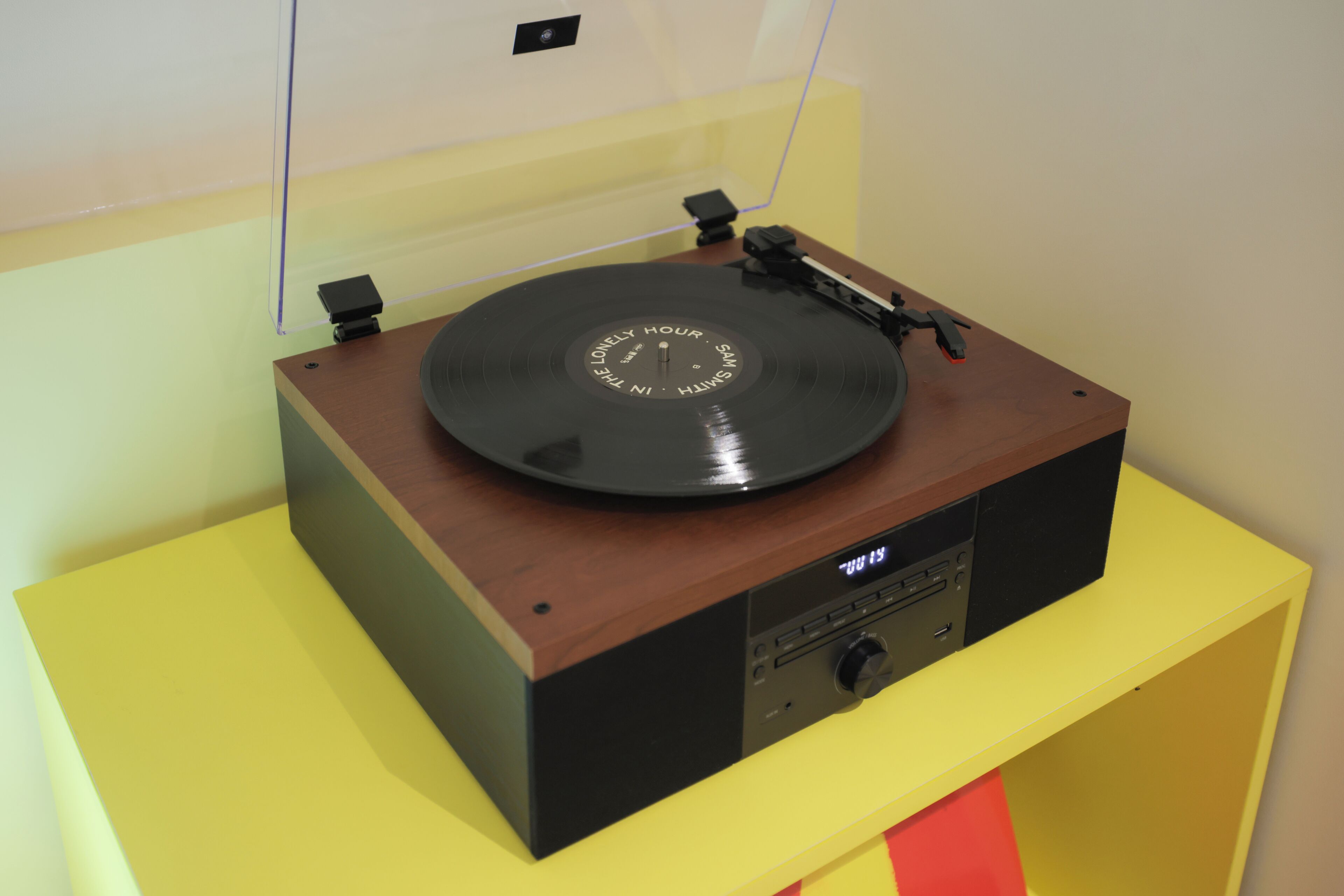 A turntable on a wooden table with a yellow base.