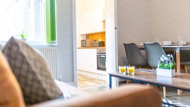 Ein modernes Wohnzimmer mit einer Couch, einem Couchtisch und Blick auf einen Küchenbereich.