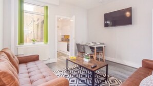Ein modernes Wohnzimmer mit einem braunen Sofa, einem Couchtisch und einem an der Wand montierten Fernseher.