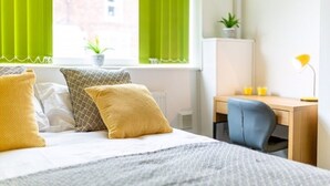 Ein ordentlich eingerichtetes Hotelzimmer mit einem Bett, einem Schreibtisch und einem Stuhl.