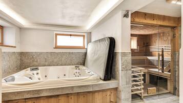 A modern bathroom with a freestanding bathtub, wooden accents, a glass shower enclosure, and a small window.