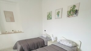 A bedroom with two beds, a nightstand, a mirror, and wall art. - A Pochi Kilometri dal Mare di Sabaudia e dal Parco del Circeo, Piscina Esterna (Zona Industriale Borgo San Donato)
