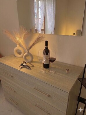 Une commode en bois sur laquelle sont posés une bouteille de vin et deux verres.