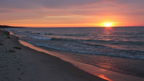 Una playa al atardecer con olas y cielo despejado.