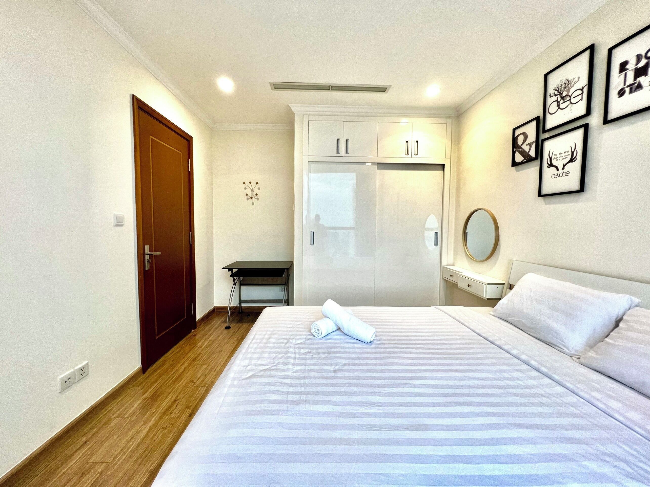 A hotel room with a bed, a wardrobe, a desk, and a mirror.