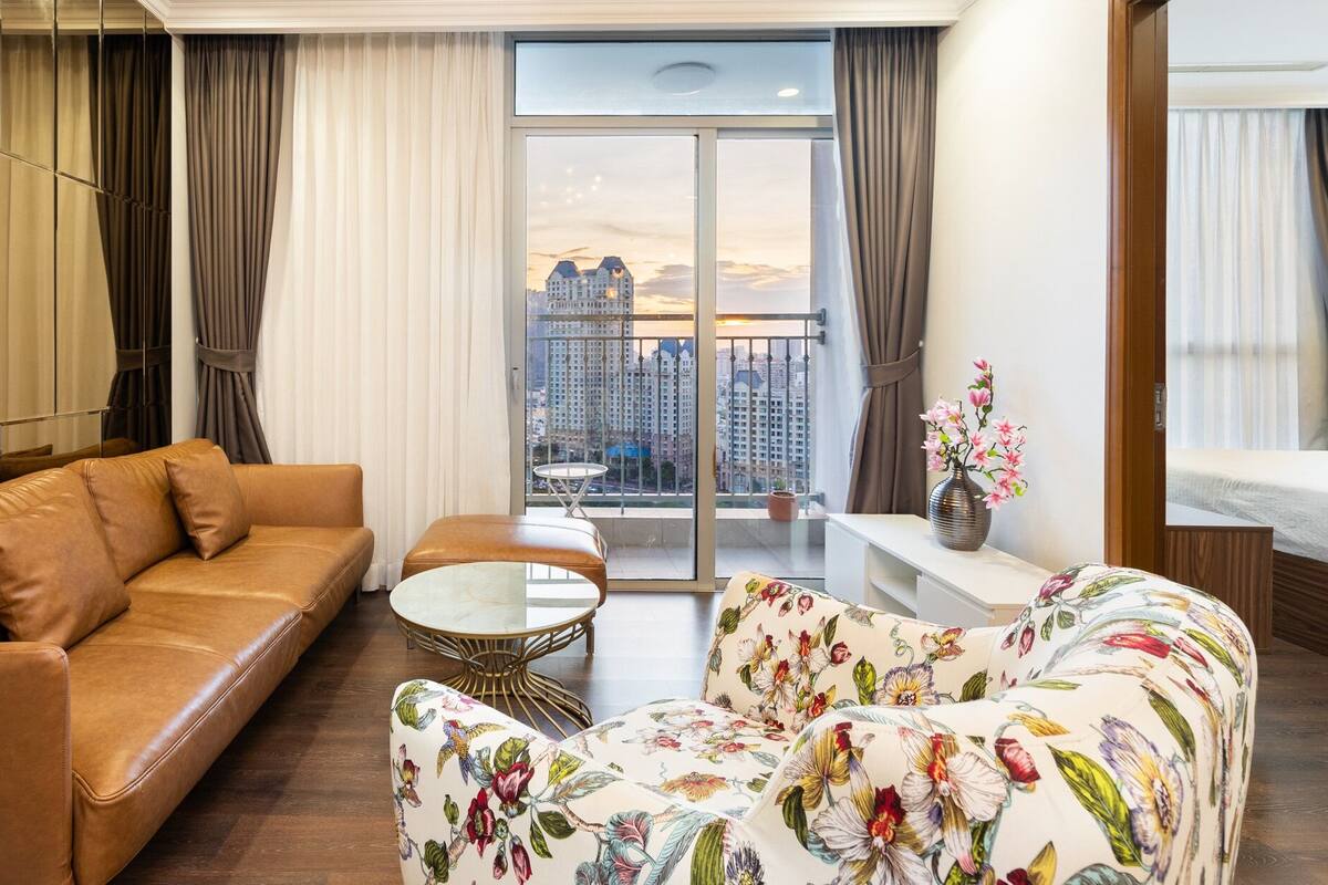 Una sala de estar moderna con un sofá de cuero, un sillón floral y una pequeña mesa redonda.