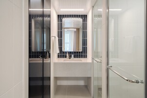 Un baño moderno con cabina de ducha de vidrio, tocador con espejo y una toalla colgada en la pared.