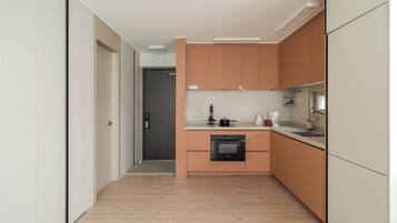 A modern kitchen with wooden cabinets, a built-in oven, and a countertop with a kettle and coffee maker.