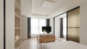 Une chambre moderne équipée d’un lit, d’un bureau, d’une télévision et d’armoires intégrées.