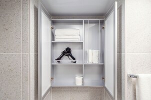A walk-in closet with shelves, a hanging rack, and a toilet paper roll.