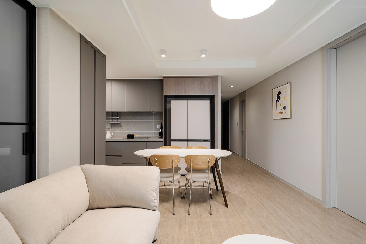 A modern living room with a sofa, a dining table with chairs, and a kitchen area in the background.