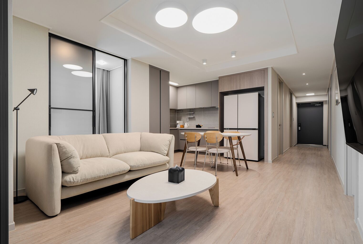 A modern living room with a sofa, a coffee table, and a dining area with chairs.