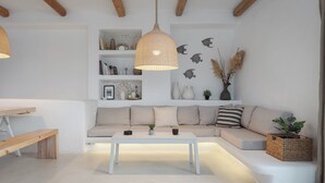 Un salon moderne avec un canapé blanc, un banc en bois, une table basse blanche et un luminaire suspendu.