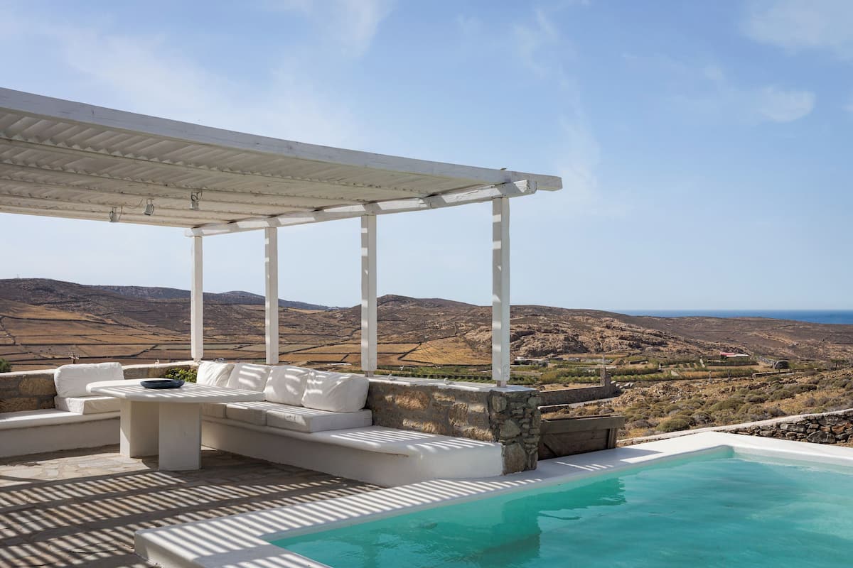 Ein Poolbereich mit weißer Sitzgruppe und einer Pergola.