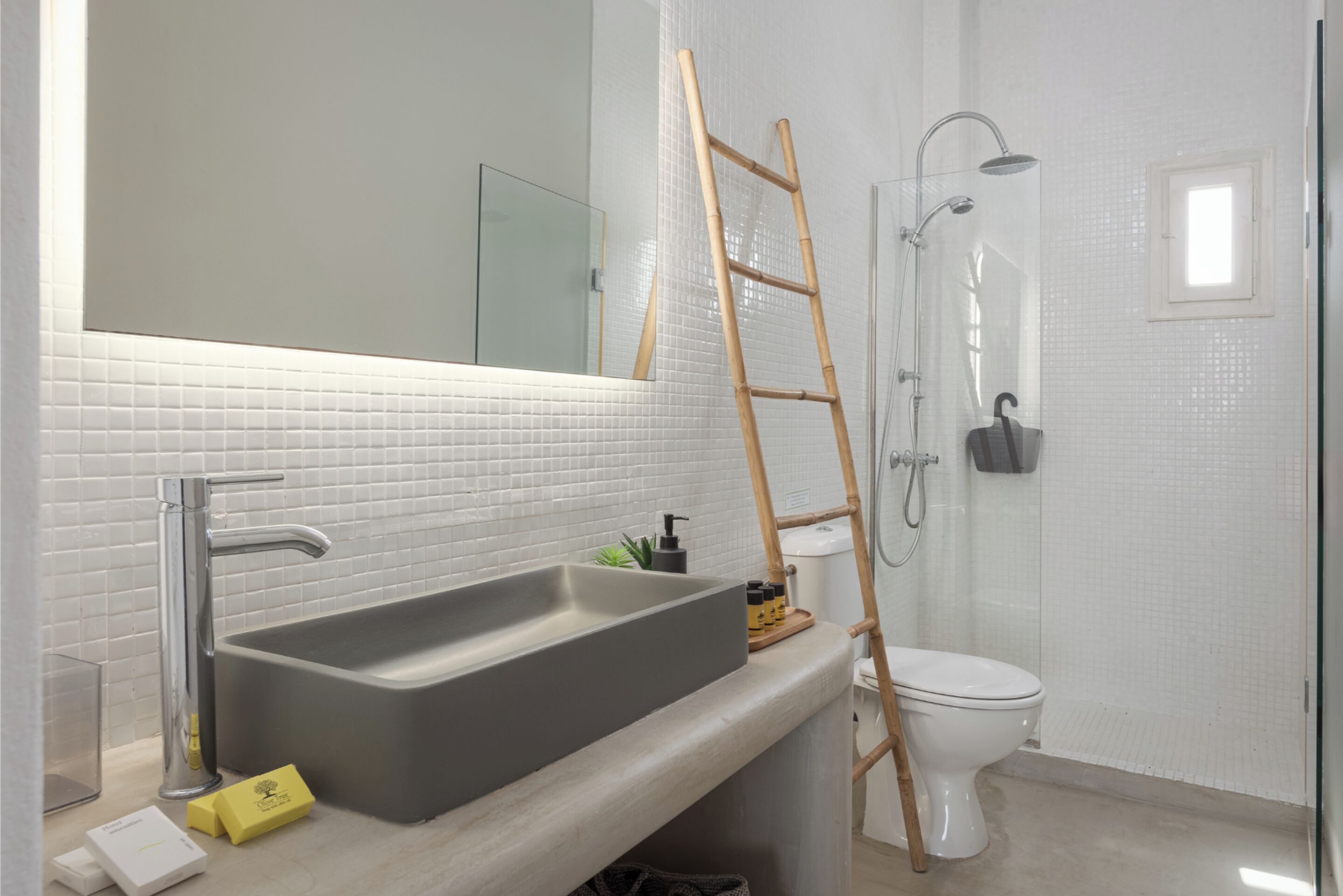 A bathroom with a large sink, a mirror, a toilet, and a shower.