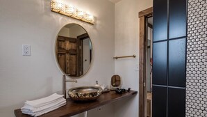 A bathroom with a wooden vanity, a large oval mirror, and a decorative sink. - Double the Comfort | Travel Together (Prescott)