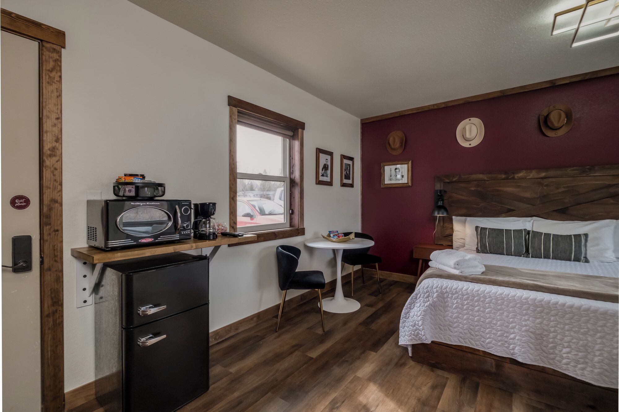 A compact hotel room with a bed, a small desk with a microwave, a coffee maker, and a chair.