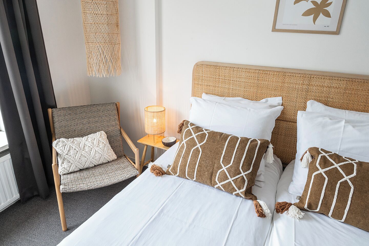 Ein Hotelzimmer mit einem Bett, einem Sessel, einem Nachttisch und einer Wandlampe.
