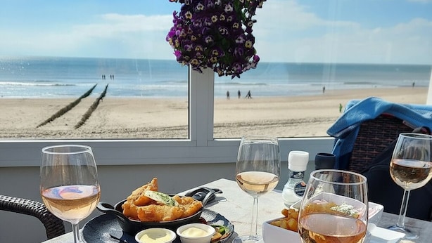 Ein Tisch mit Nachos, Weingläsern und Blick auf den Strand.