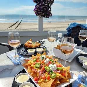 Ett bord med nachochips, vinglas och utsikt över stranden.