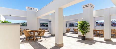 An outdoor patio area with multiple seating arrangements and a potted plant.