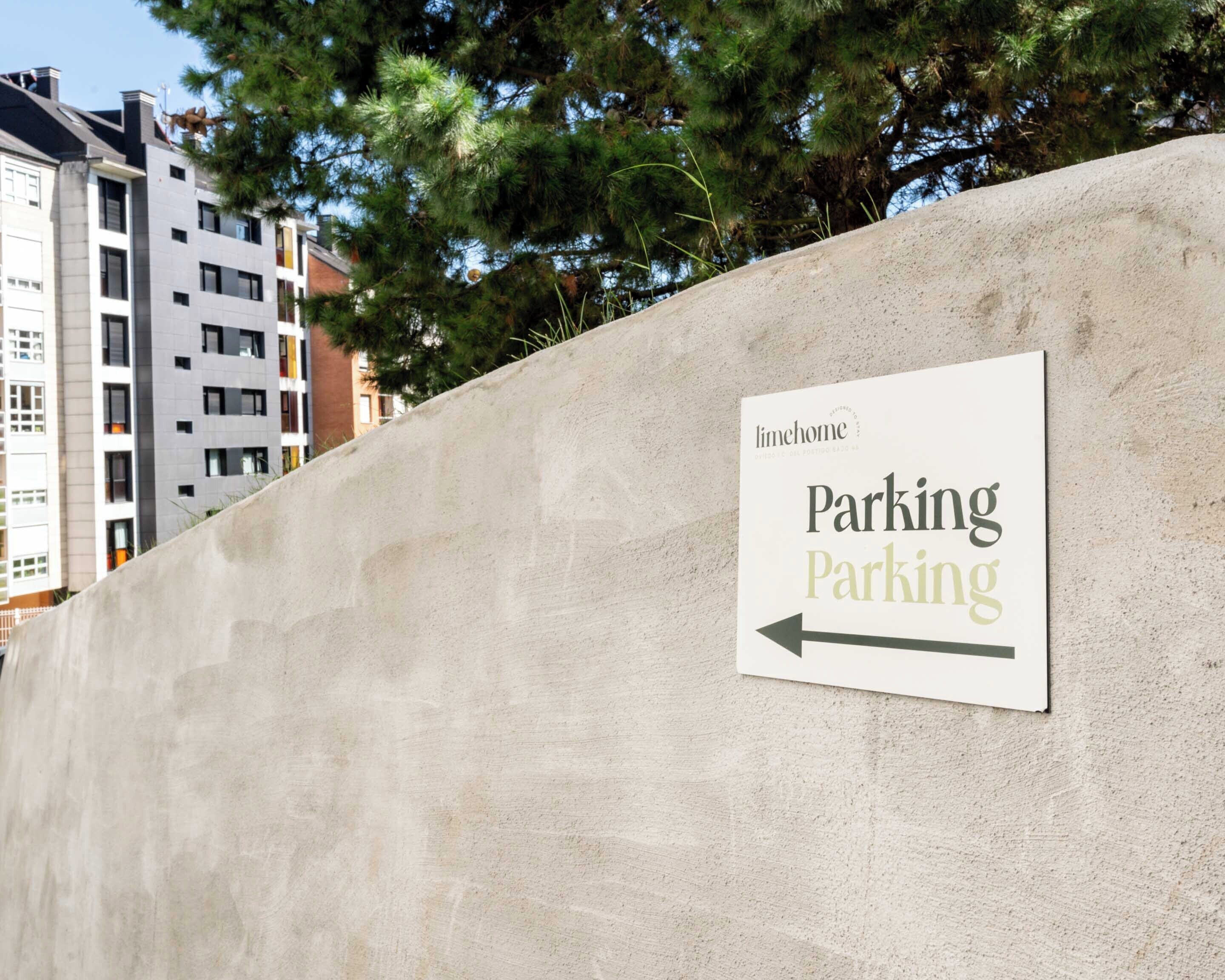 A sign on a concrete wall indicating 'Parking' with an arrow pointing to the left.