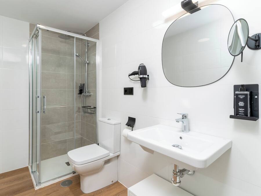 A modern bathroom with a glass-enclosed shower, a white toilet, a sink with a mirror, and a towel rack.