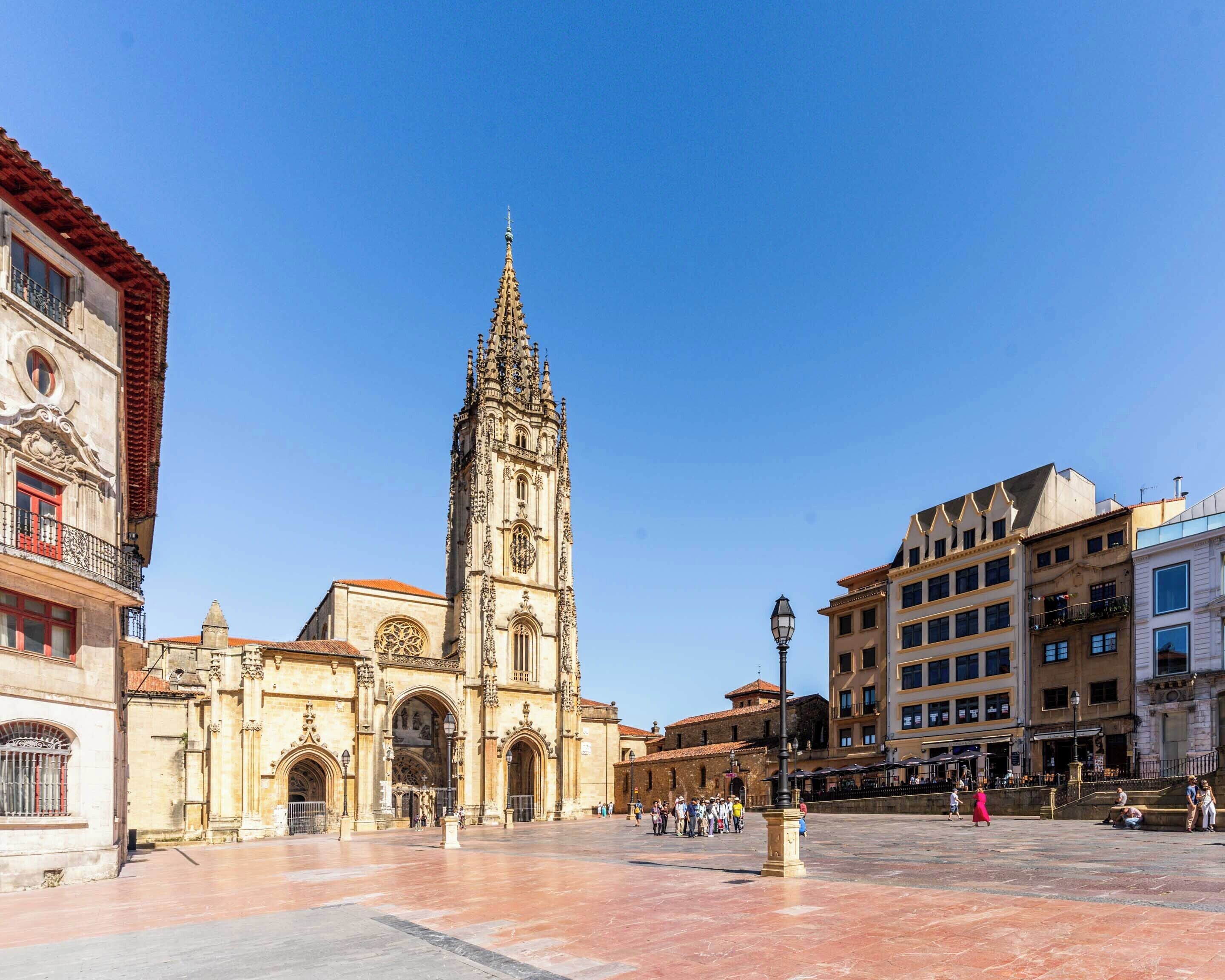 Una plaza histórica con una catedral destacada que presenta una intrincada arquitectura gótica, una amplia zona abierta y edificios circundantes con fachadas variadas.
