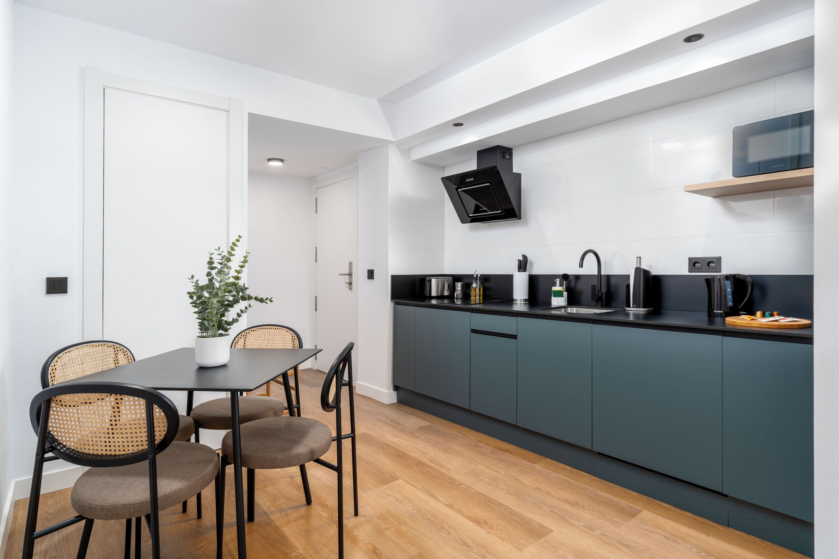 Une cuisine moderne avec des meubles gris, un plan de travail noir et un four à micro-ondes encastré.