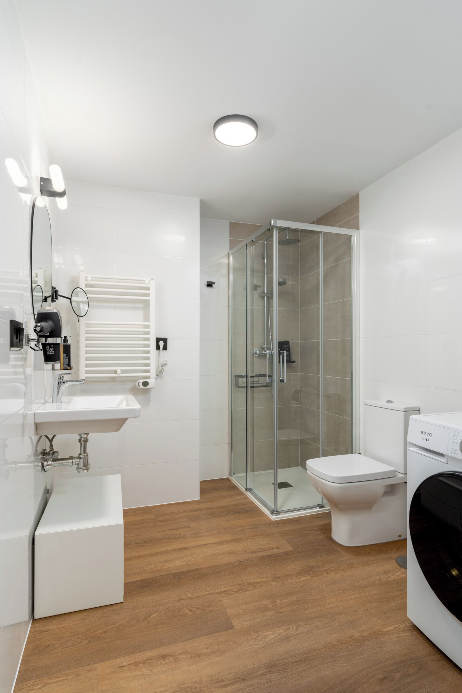 A modern bathroom with a glass-enclosed shower, a white sink, and a toilet.