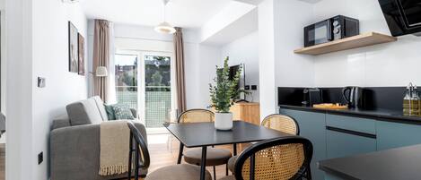 A modern kitchen with a dining area, a sofa, and a potted plant.