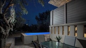 Un patio exterior con una mesa de vidrio, sillas y una pequeña piscina.