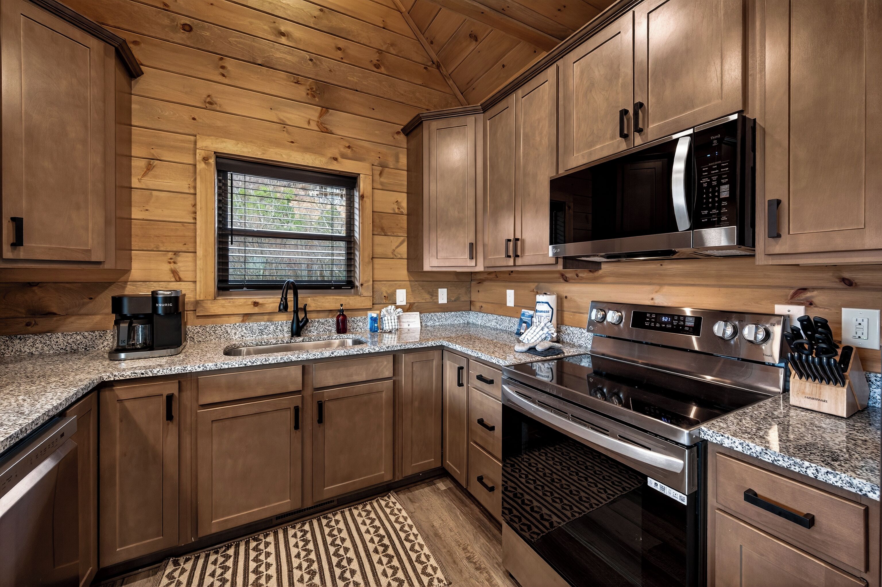 A kitchen with wooden cabinets, a stainless steel microwave, a built-in oven, and a coffee maker.