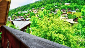 Un balcón de madera con vistas a un pueblo con casas tradicionales en un valle verde.