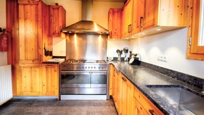 Una cocina con armarios de madera, estufa de acero inoxidable y encimera de granito.