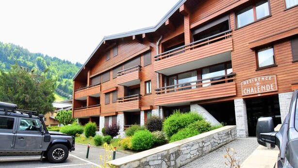 Un hotel de varios pisos con fachada de madera, balcones y un cartel que dice "Residence Chalende".