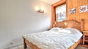 Una cama de madera con colcha blanca en una habitación con paredes de madera y una ventana.