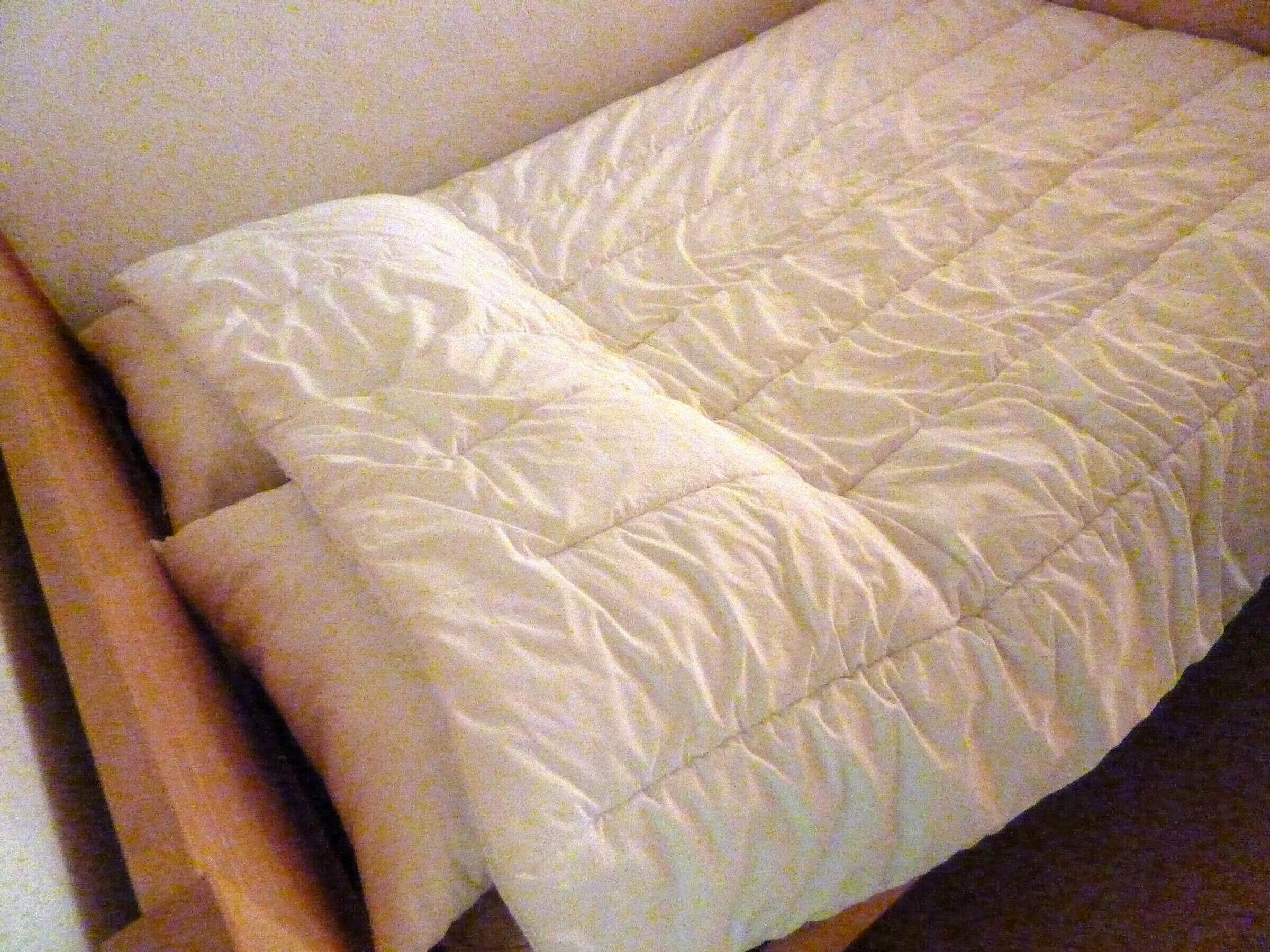 A bed with a quilted white duvet.