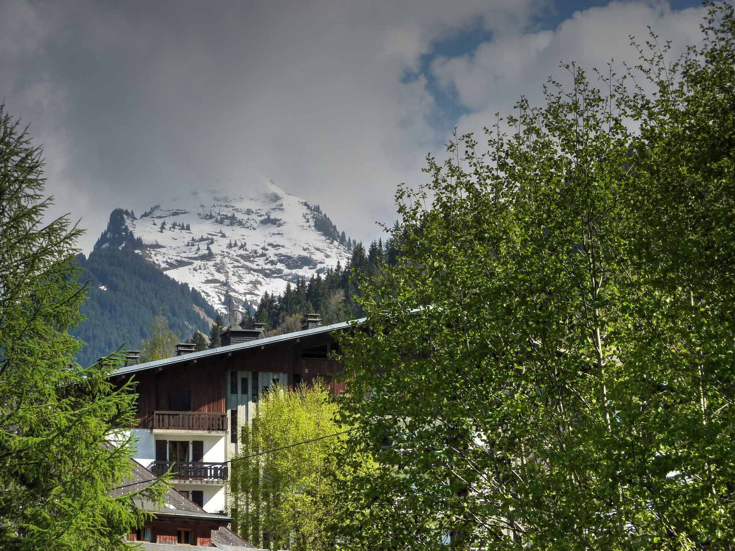 Ein Berg mit schneebedeckten Gipfeln und ein Gebäude mit Balkon im Vordergrund.