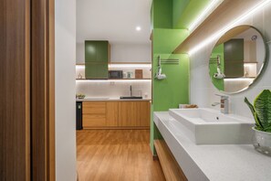 A modern bathroom with a white sink, green walls, and a wooden floor. - Q Apartment Da Nang (Da Nang)