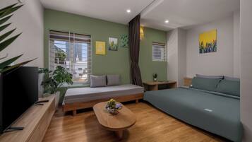 Une chambre moderne avec un canapé, un lit, une table basse en bois agrémentée d’une plante, et des œuvres d’art accrochées aux murs.