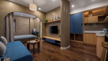 A modern living room with a blue sofa, a small coffee table, and a TV mounted on the wall.