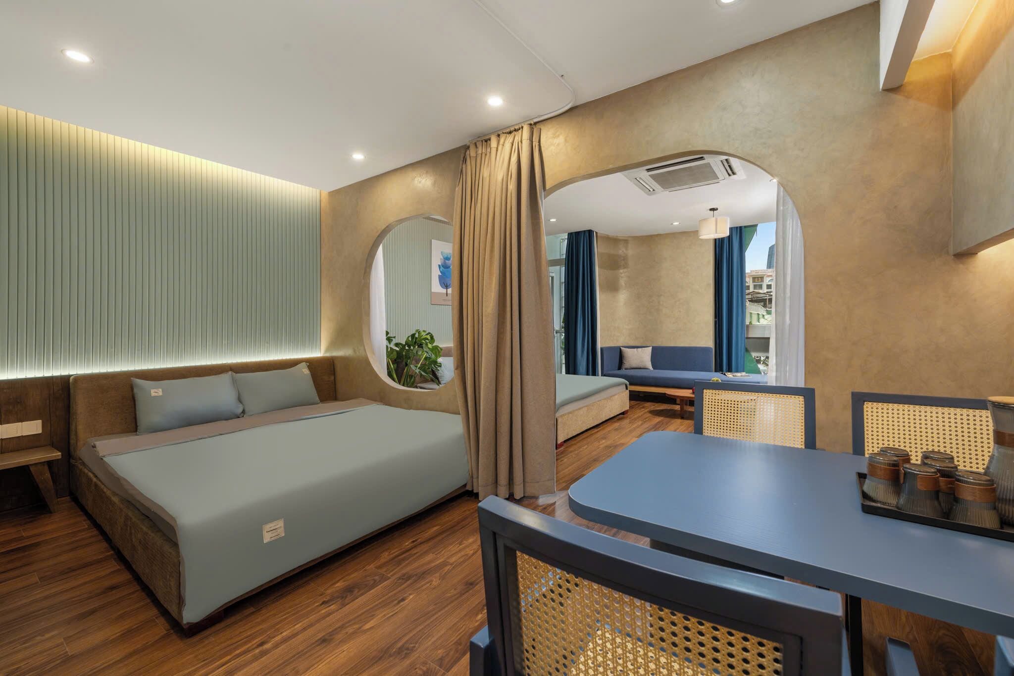 Ein modernes Hotelzimmer mit Bett, Sitzecke, Esstisch und Blick auf die Stadt.