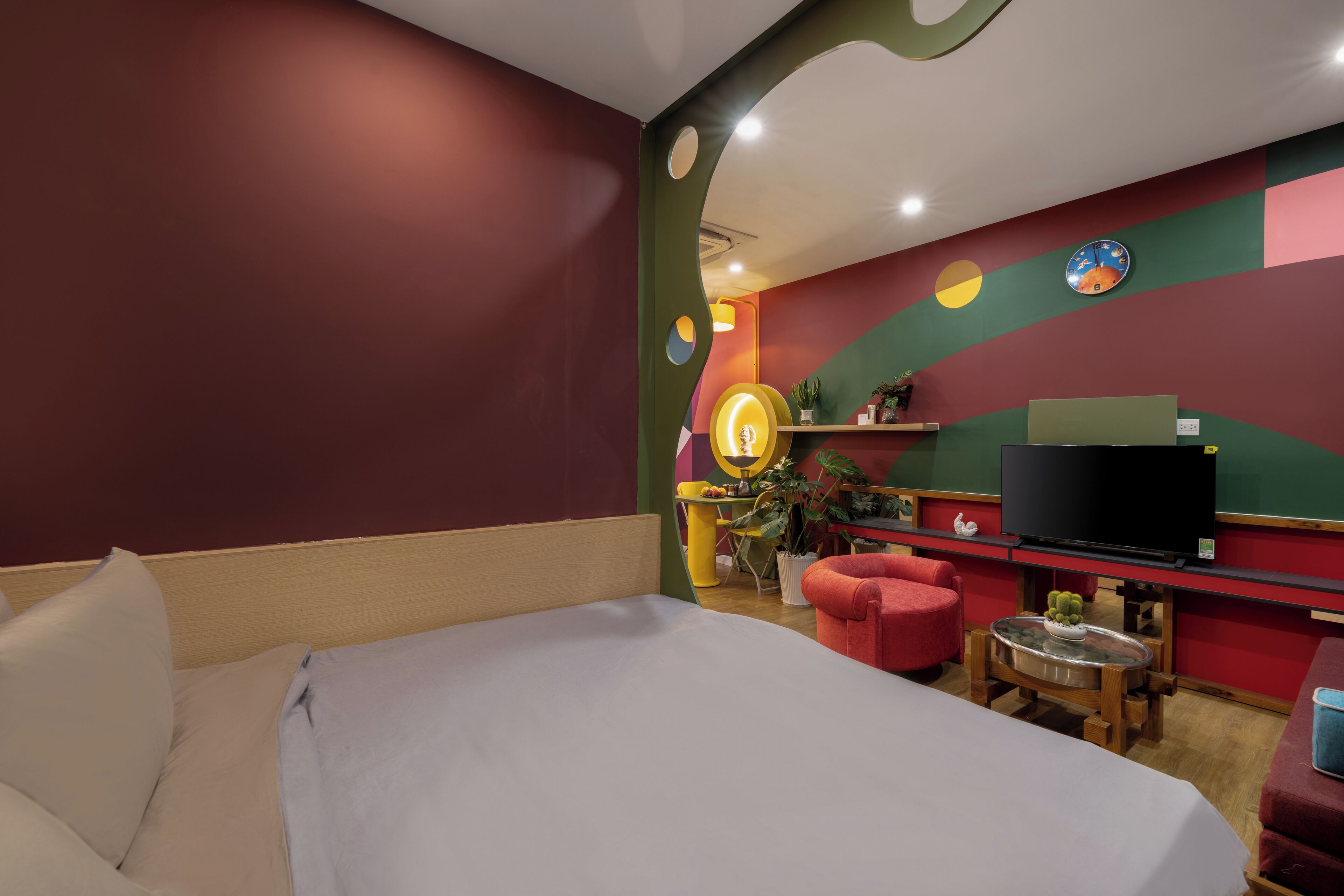A hotel room with a bed, a desk, a television, and a wall clock.