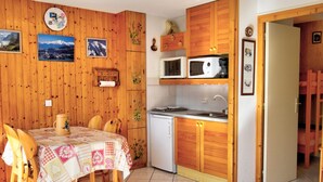 A cozy kitchen with wooden cabinets, a dining table with chairs, and a refrigerator. - Cozy studio near Morzine center for 4 ppl. (Morzine)