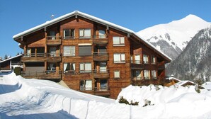 A multi-story wooden chalet with balconies, set against a snowy mountain backdrop. - Cozy studio near Morzine center for 4 ppl. (Morzine)
