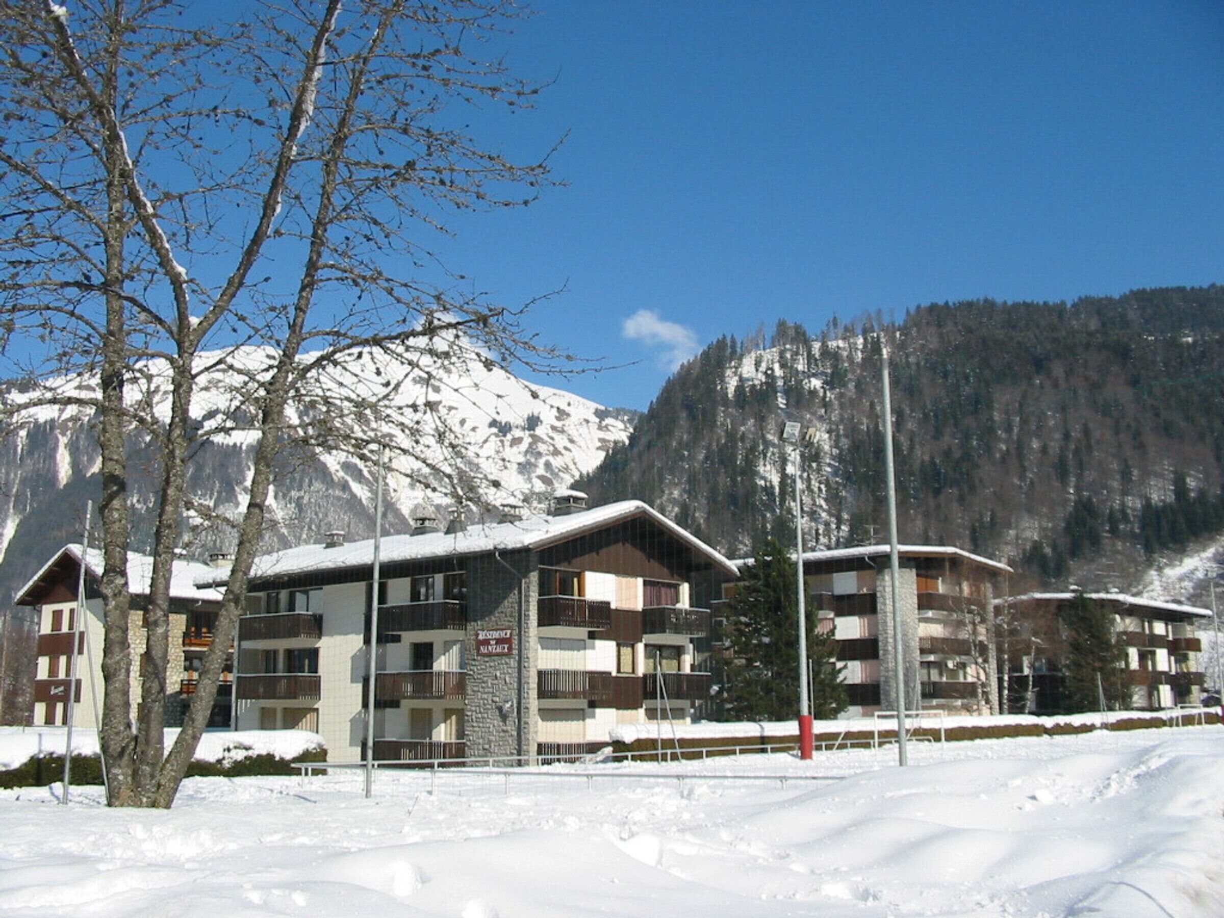 Un edificio cubierto de nieve con varios balcones, rodeado de nieve y montañas.