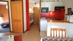 A compact kitchen with a microwave, stove, and white cabinets.