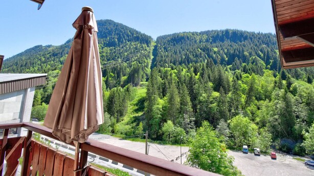 A balcony with a wooden railing overlooking a forested valley and mountains. - Renovated studio by the cable car, parking, WiFi (Morzine)